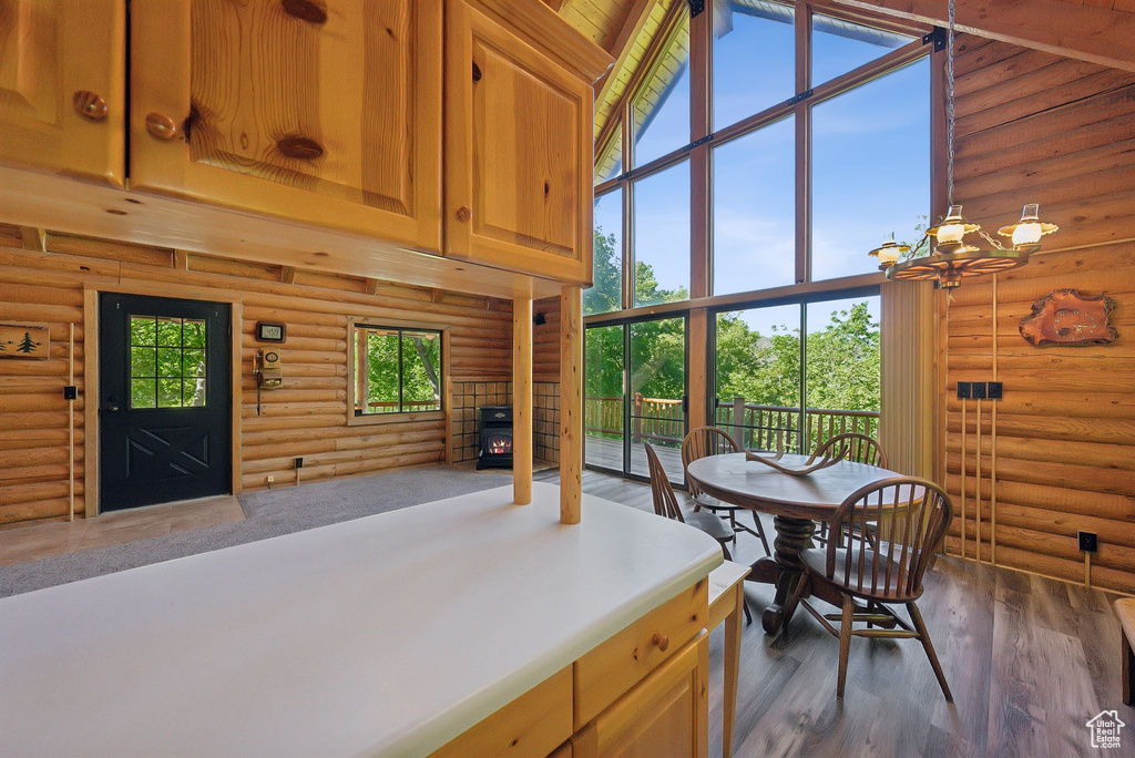 Dining room featuring a high ceiling, log walls, a chandelier, and dark wood-type flooring