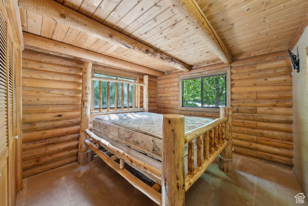Unfurnished bedroom with wood ceiling with exposed beams, carpet flooring, and log walls