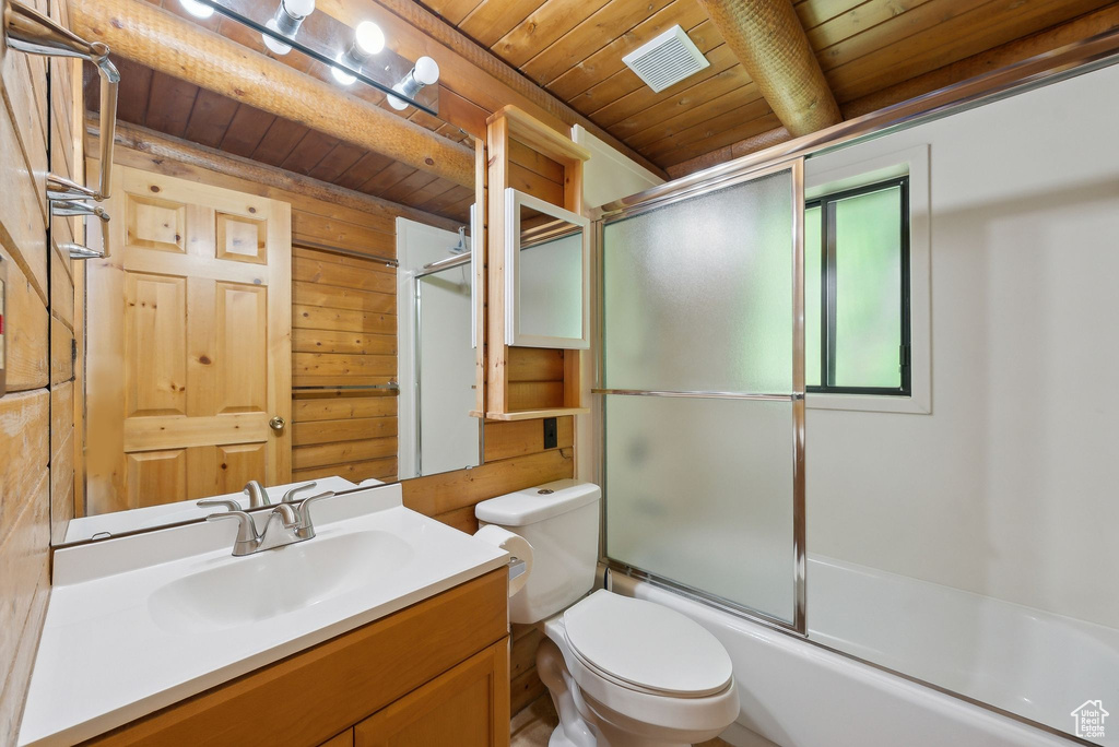 Bathroom with wood ceiling with exposed beams, vanity, shower / bath combination with glass door, and toilet