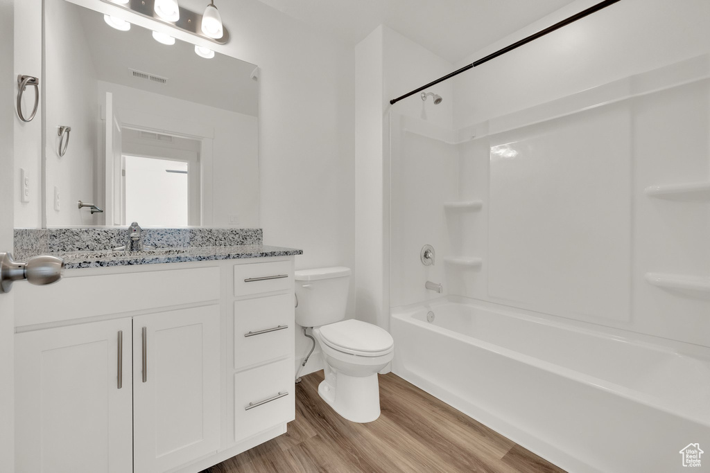 Full bathroom with toilet, wood finished floors, vanity, and washtub / shower combination