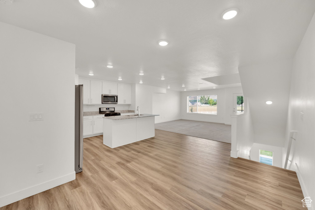 Kitchen featuring stainless steel appliances, open floor plan, recessed lighting, baseboards, and white cabinetry