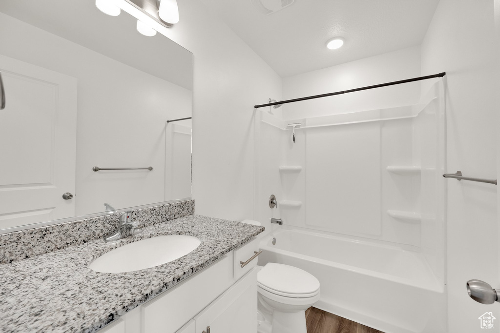 Bathroom with vanity, wood finished floors, bathing tub / shower combination, and toilet