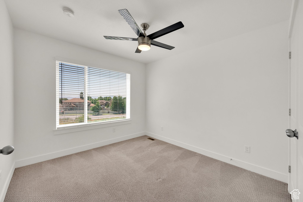 Empty room featuring baseboards, a ceiling fan, light carpet, and a smoke detector