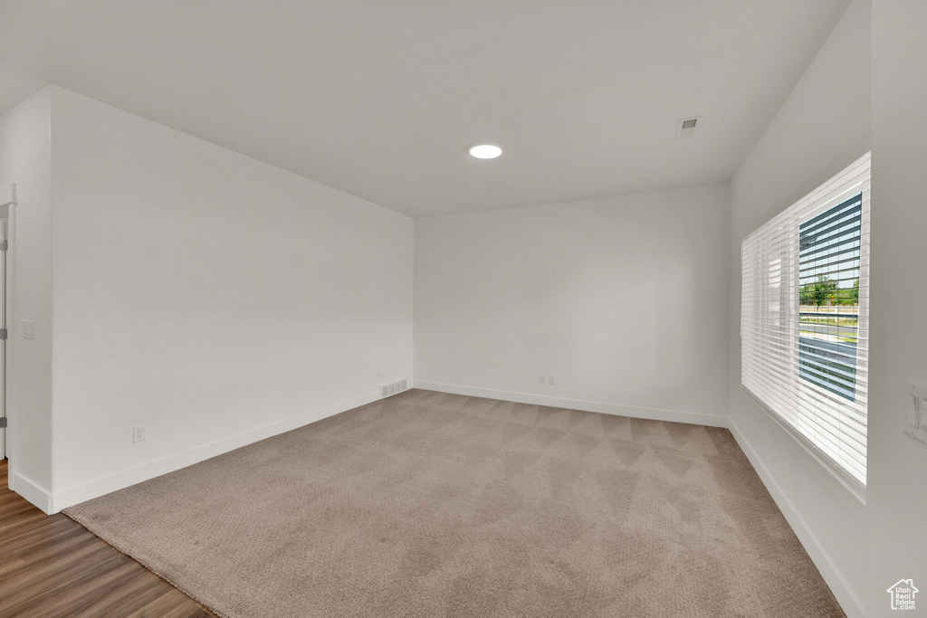 Empty room featuring baseboards, recessed lighting, and light carpet