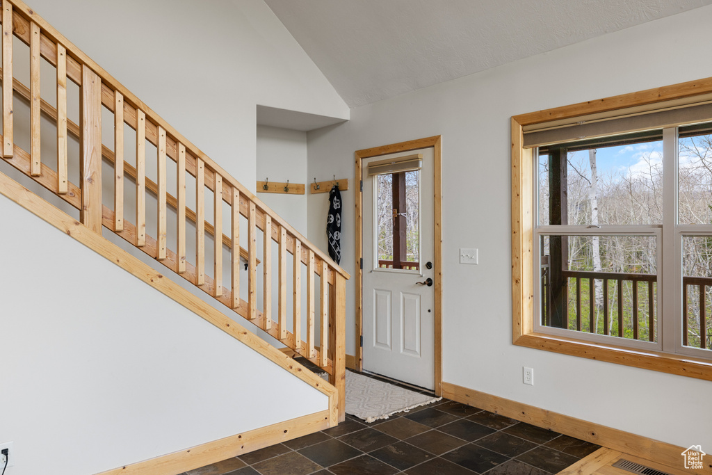 Entrance foyer with baseboards, stairs, and vaulted ceiling