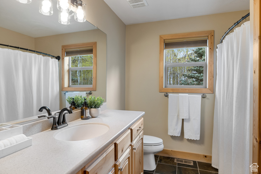 Full bath featuring toilet, vanity, baseboards, and curtained shower