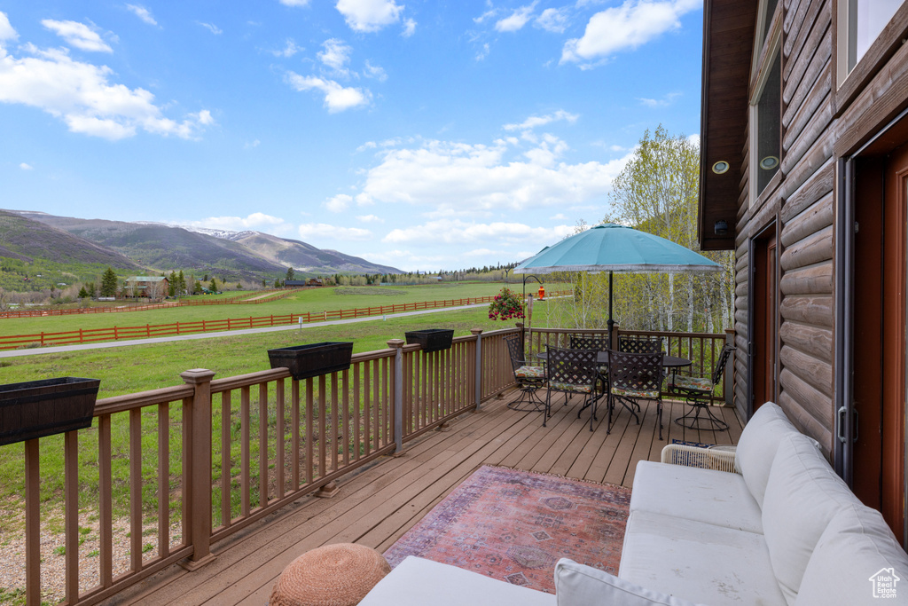 Wooden terrace with outdoor dining area, a view of rural / pastoral area, and a mountain view