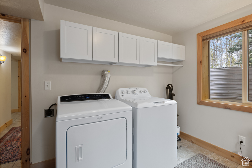 Laundry area with cabinet space, independent washer and dryer, baseboards, and light tile patterned flooring