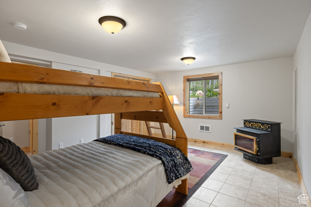 Bedroom with baseboards, a wood stove, and tile patterned flooring