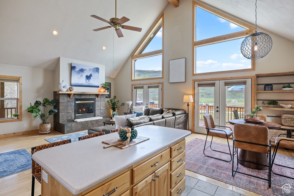 Kitchen featuring open floor plan, high vaulted ceiling, french doors, a ceiling fan, and a tile fireplace