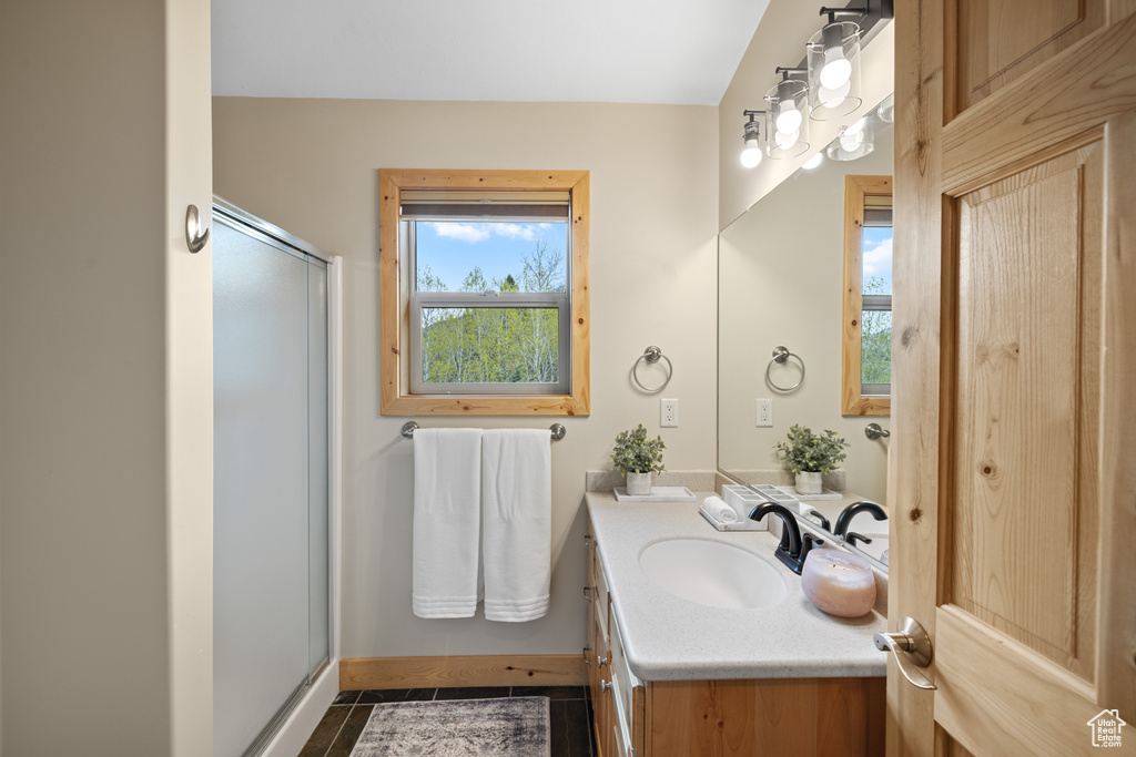 Bathroom featuring vanity, a stall shower, tile patterned flooring, and baseboards