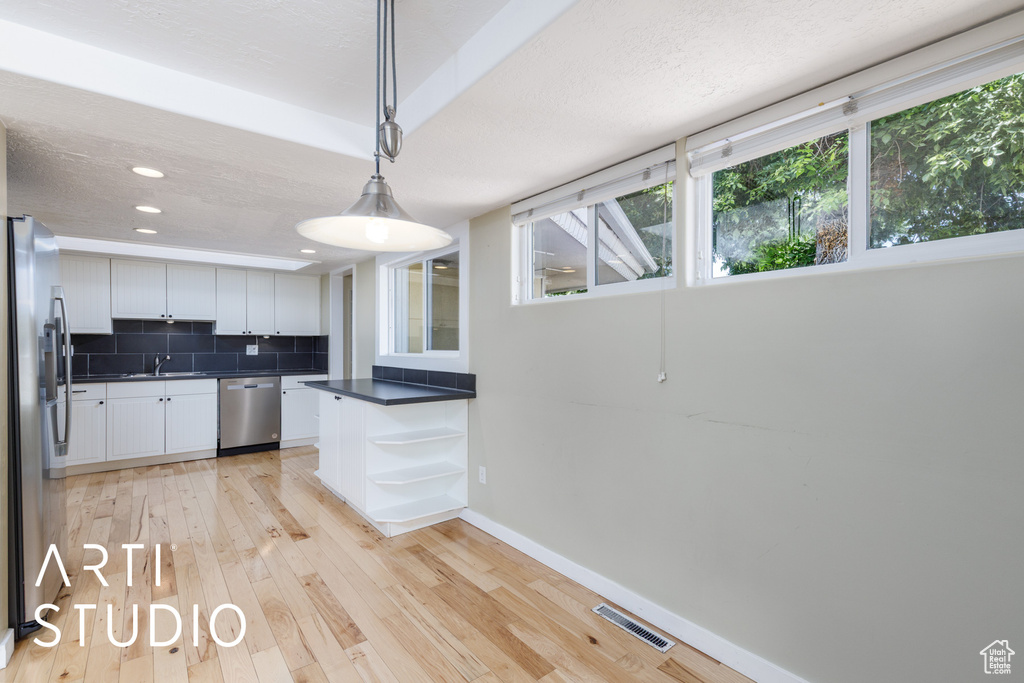 Kitchen featuring appliances with stainless steel finishes, dark countertops, white cabinetry, baseboards, and light wood finished floors