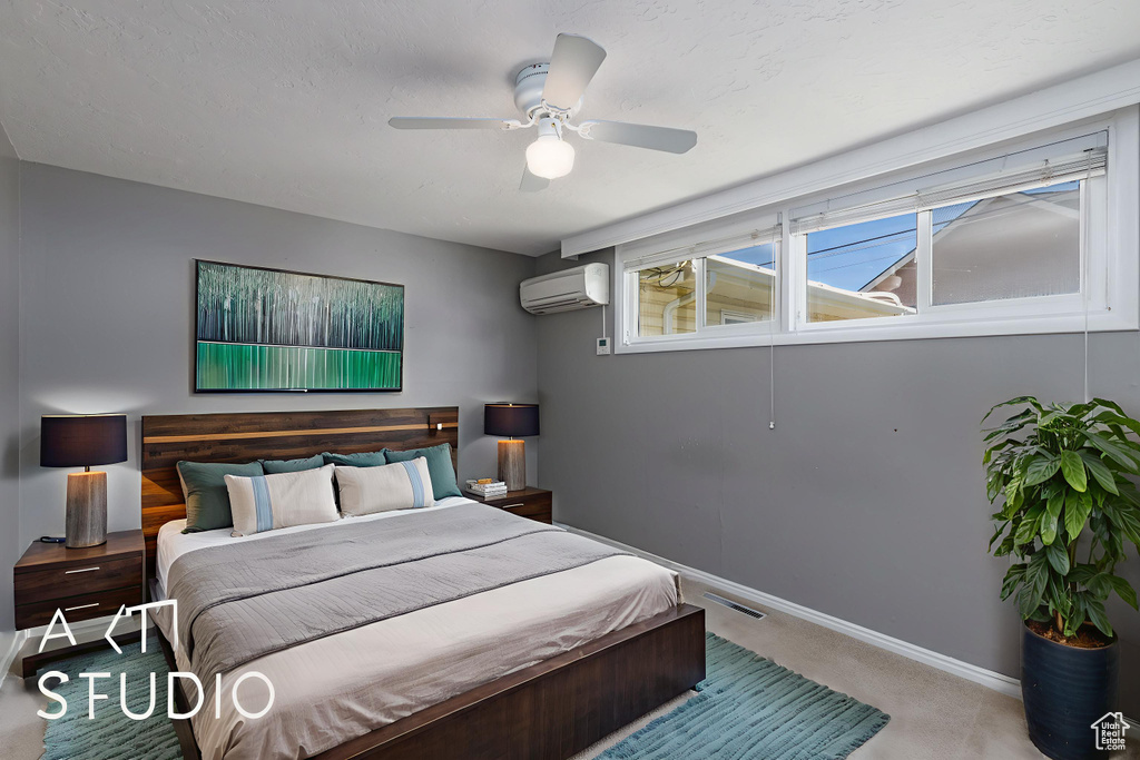 Carpeted bedroom featuring a wall mounted AC, baseboards, and ceiling fan