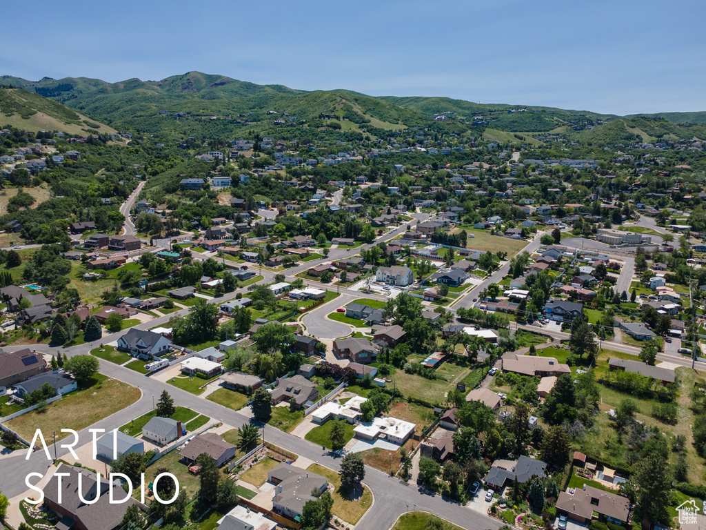 Aerial view of property and surrounding area featuring a mountain backdrop and nearby suburban area