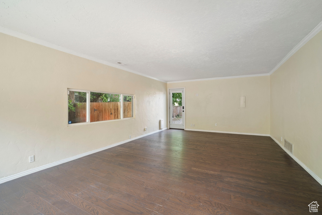 Empty room featuring wood finished floors, ornamental molding, and baseboards