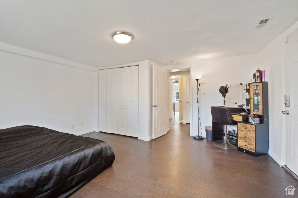 Bedroom with wood finished floors, a closet, and baseboards