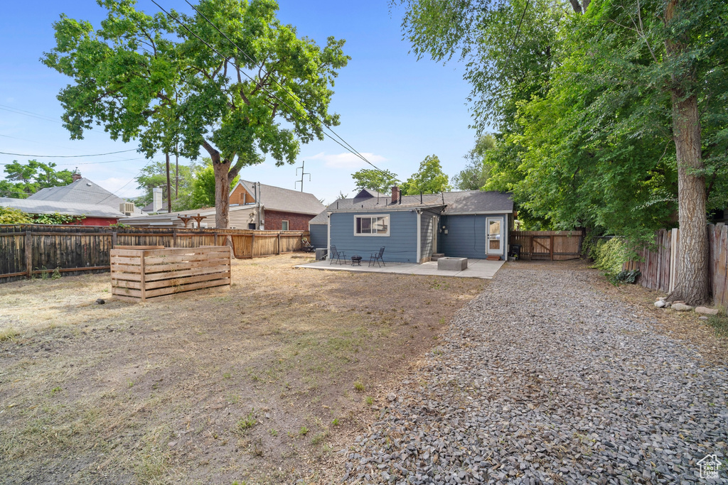 Rear view of house featuring a patio, a fenced backyard, and a chimney
