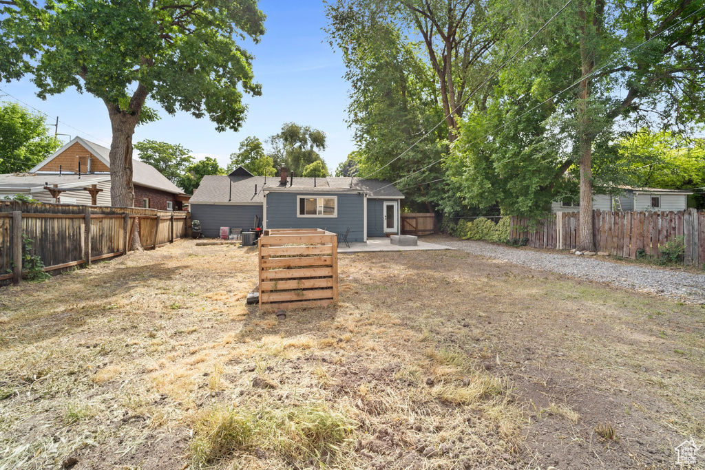 Rear view of house with a fenced backyard and a patio area