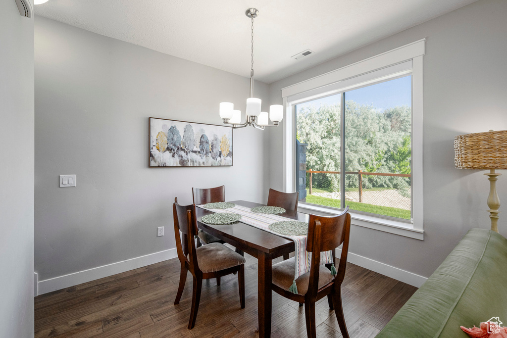 Dining room with baseboards, a chandelier, and dark wood-type flooring