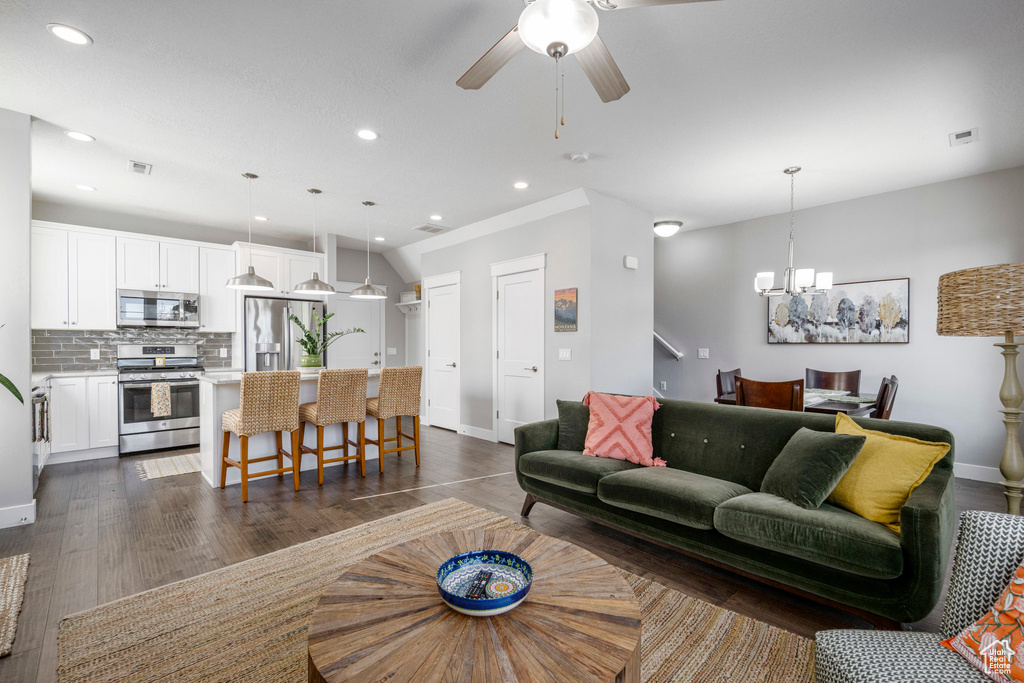 Living area featuring a chandelier, recessed lighting, baseboards, dark wood-style floors, and a ceiling fan