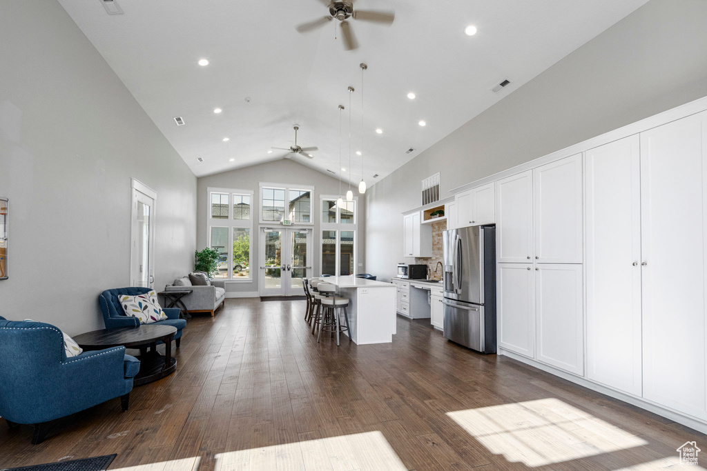 Kitchen with stainless steel fridge, a ceiling fan, open floor plan, high vaulted ceiling, and a kitchen breakfast bar