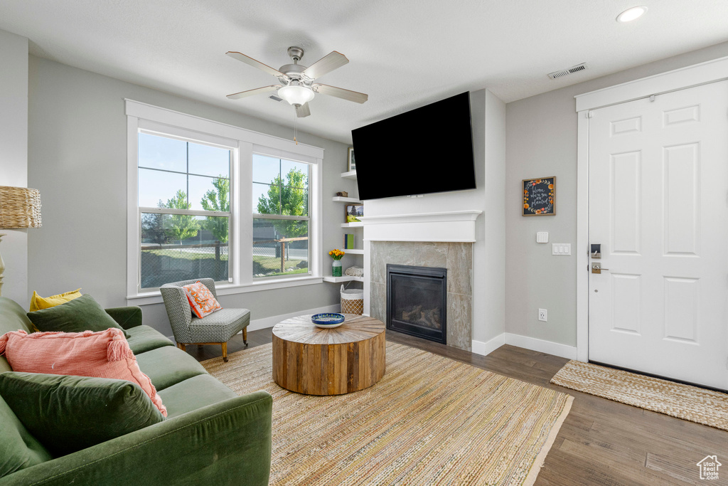 Living area with baseboards, a tile fireplace, wood finished floors, ceiling fan, and recessed lighting