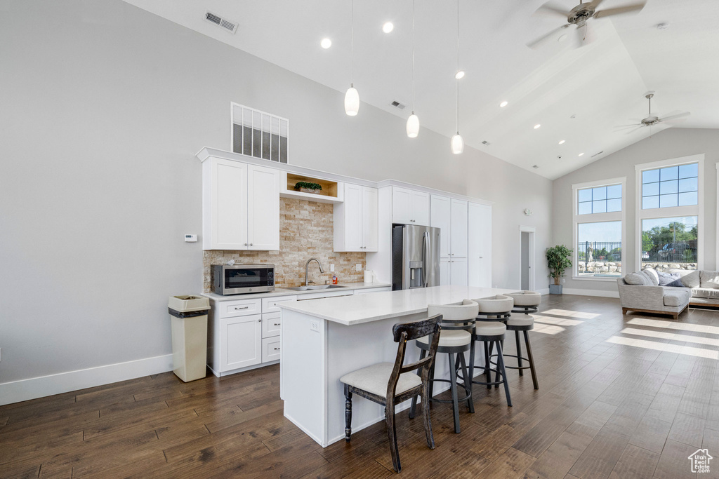 Kitchen with appliances with stainless steel finishes, a sink, high vaulted ceiling, a ceiling fan, and a center island