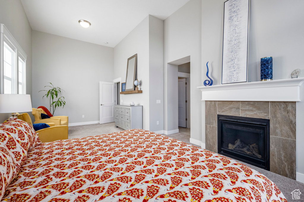 Bedroom with carpet floors, baseboards, a towering ceiling, and a tile fireplace