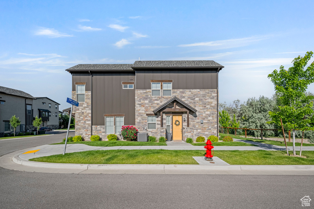 Contemporary home featuring stone siding, central AC unit, a shingled roof, board and batten siding, and a front yard
