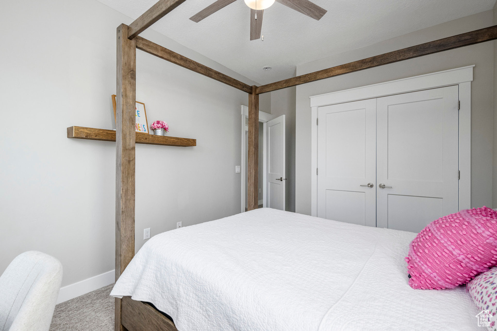 Carpeted bedroom featuring baseboards, a closet, and ceiling fan