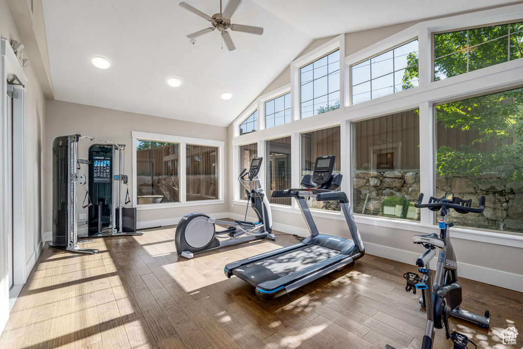 Exercise room with ceiling fan, hardwood / wood-style flooring, high vaulted ceiling, and baseboards