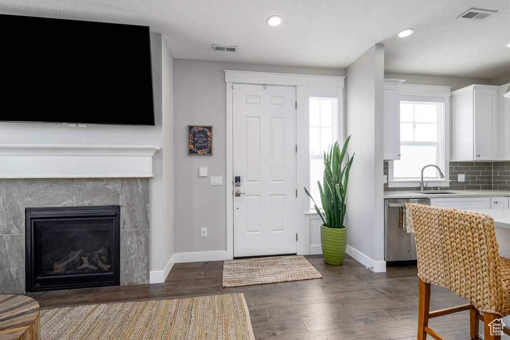 Foyer entrance with dark wood-style flooring, baseboards, recessed lighting, and a fireplace
