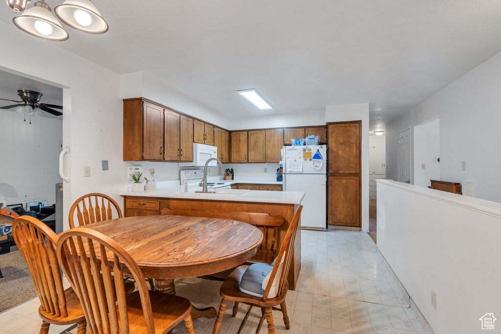 Kitchen featuring white appliances, light flooring, light countertops, and a peninsula