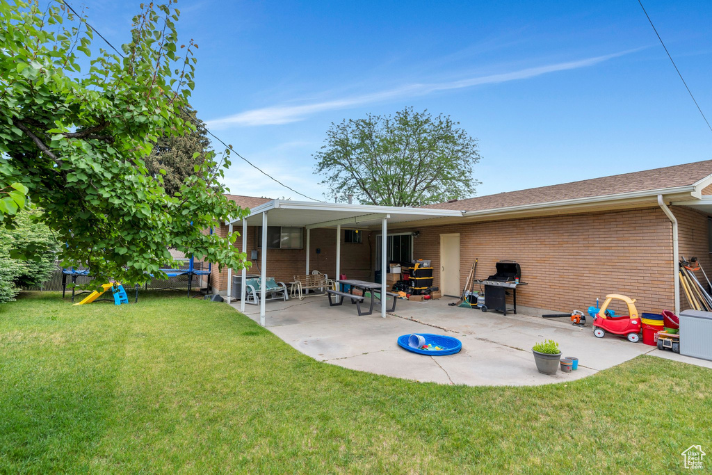 Back of property featuring a trampoline, brick siding, and a patio area