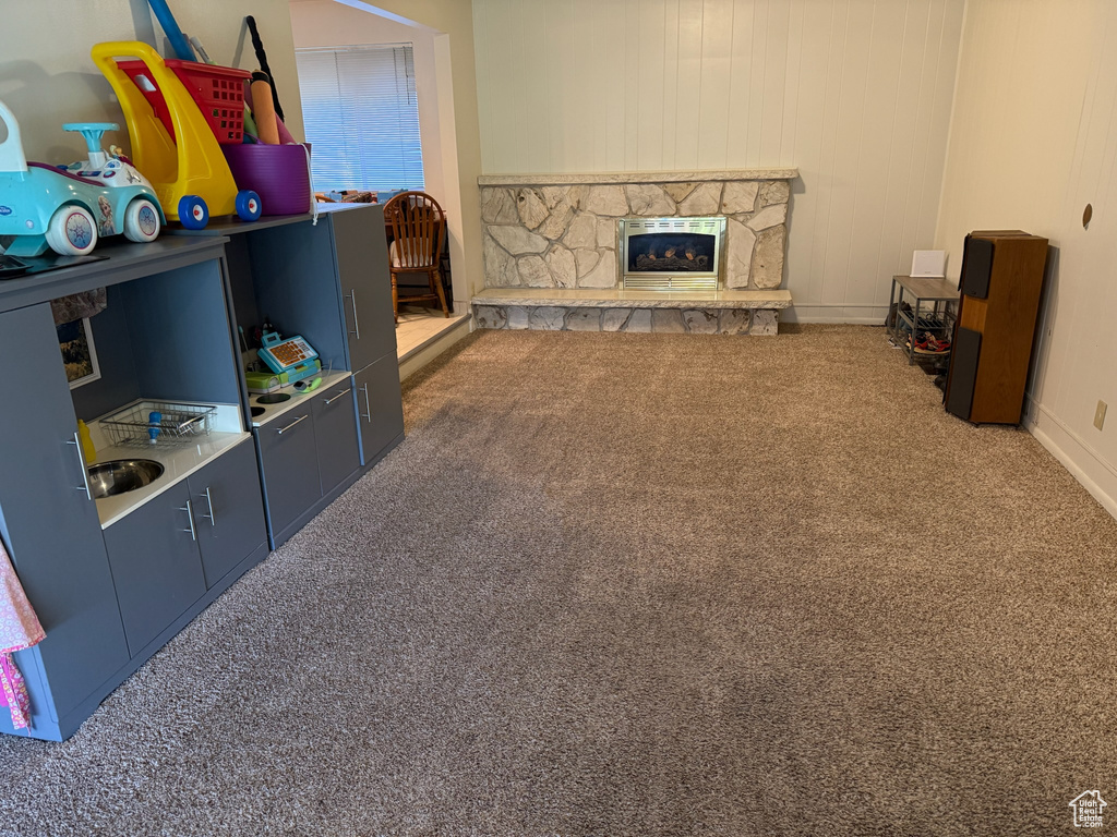 Living area with carpet floors and a stone fireplace