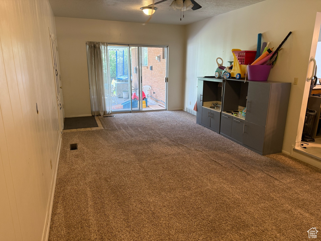 Carpeted living room featuring a ceiling fan and baseboards