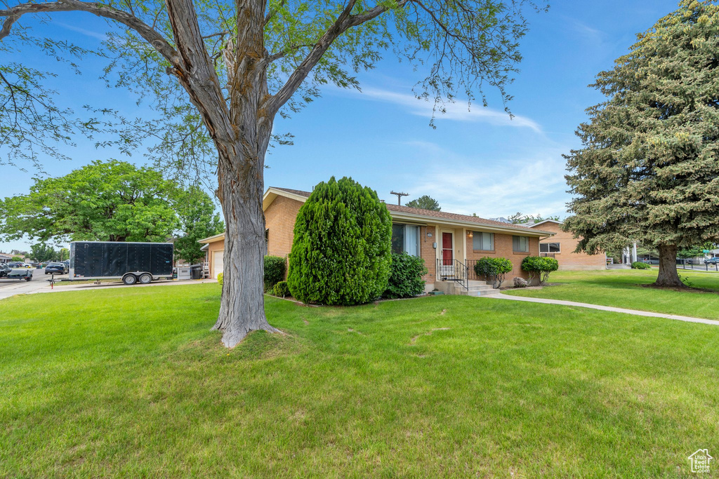 View of front of property with a front lawn, brick siding, and a garage