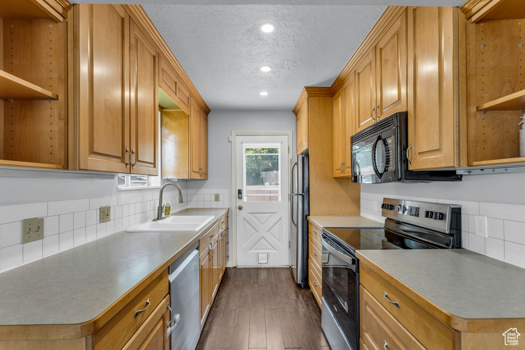Kitchen with stainless steel appliances, a sink, open shelves, dark wood-type flooring, and a textured ceiling