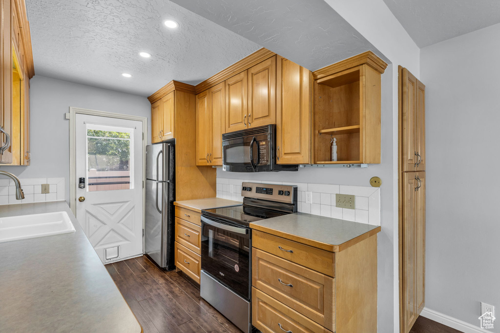 Kitchen featuring appliances with stainless steel finishes, a sink, recessed lighting, decorative backsplash, and dark wood-style floors