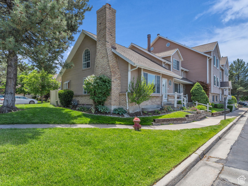 View of side of home featuring a lawn, a chimney, and brick siding