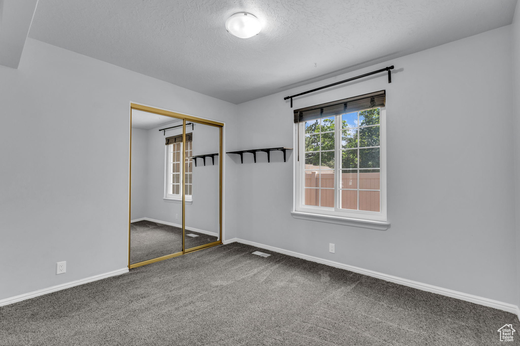Carpeted spare room featuring a textured ceiling and baseboards