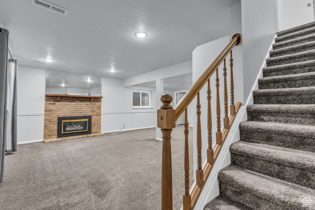 Staircase featuring carpet, baseboards, a fireplace, and recessed lighting