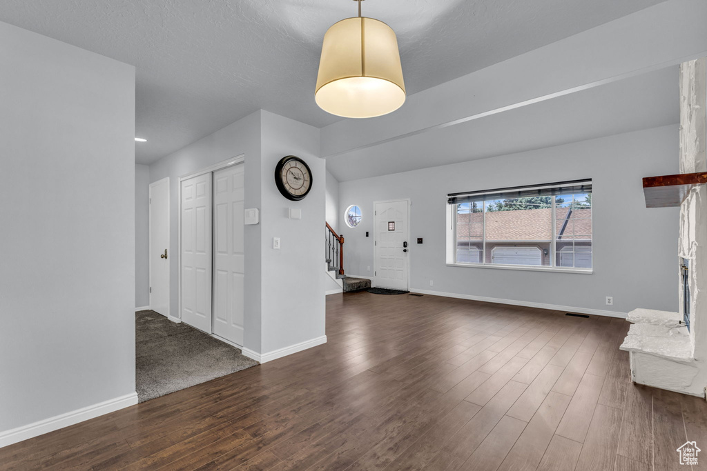 Unfurnished living room featuring stairway, dark wood-style flooring, and baseboards