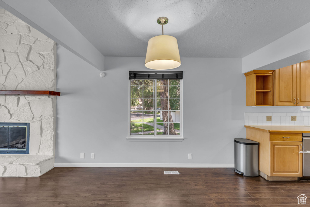 Unfurnished living room featuring dark wood-style floors, a textured ceiling, baseboards, and a fireplace