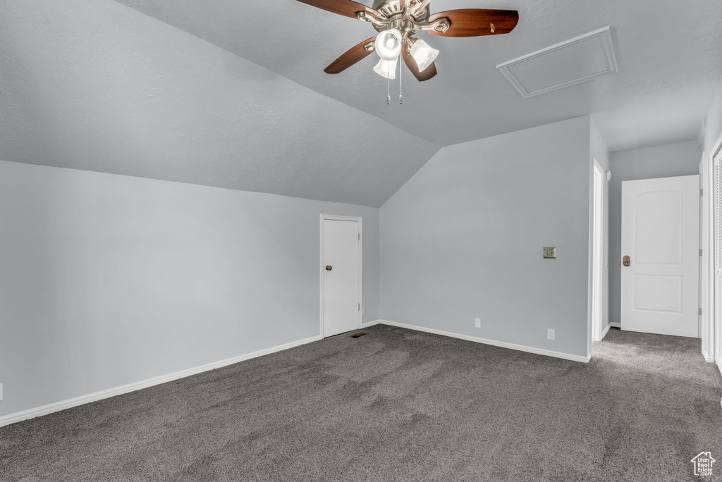 Bonus room with a ceiling fan, dark carpet, vaulted ceiling, and baseboards