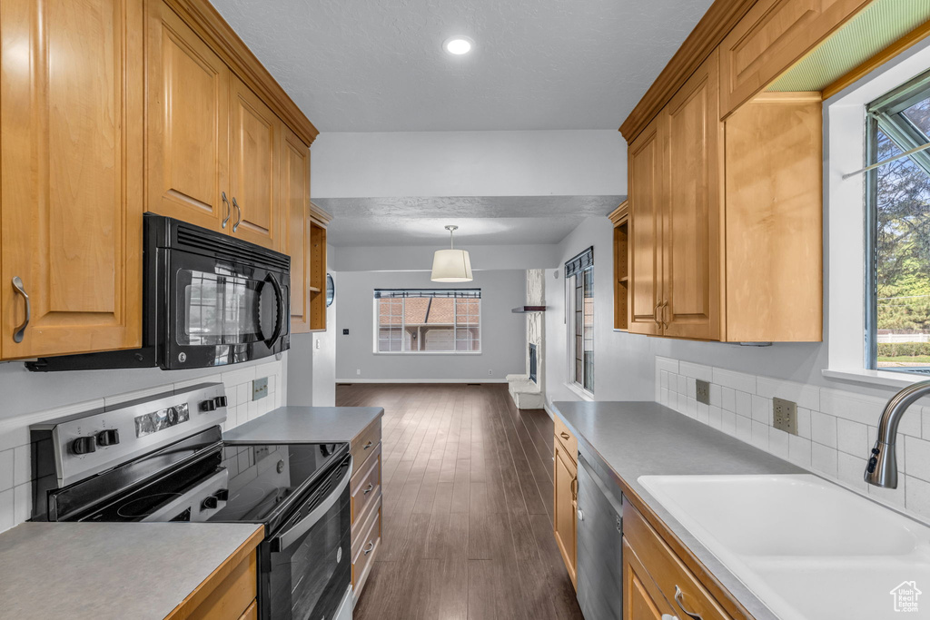 Kitchen featuring appliances with stainless steel finishes, a sink, dark wood-type flooring, recessed lighting, and hanging light fixtures