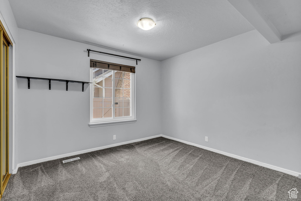Empty room with carpet, a textured ceiling, and baseboards