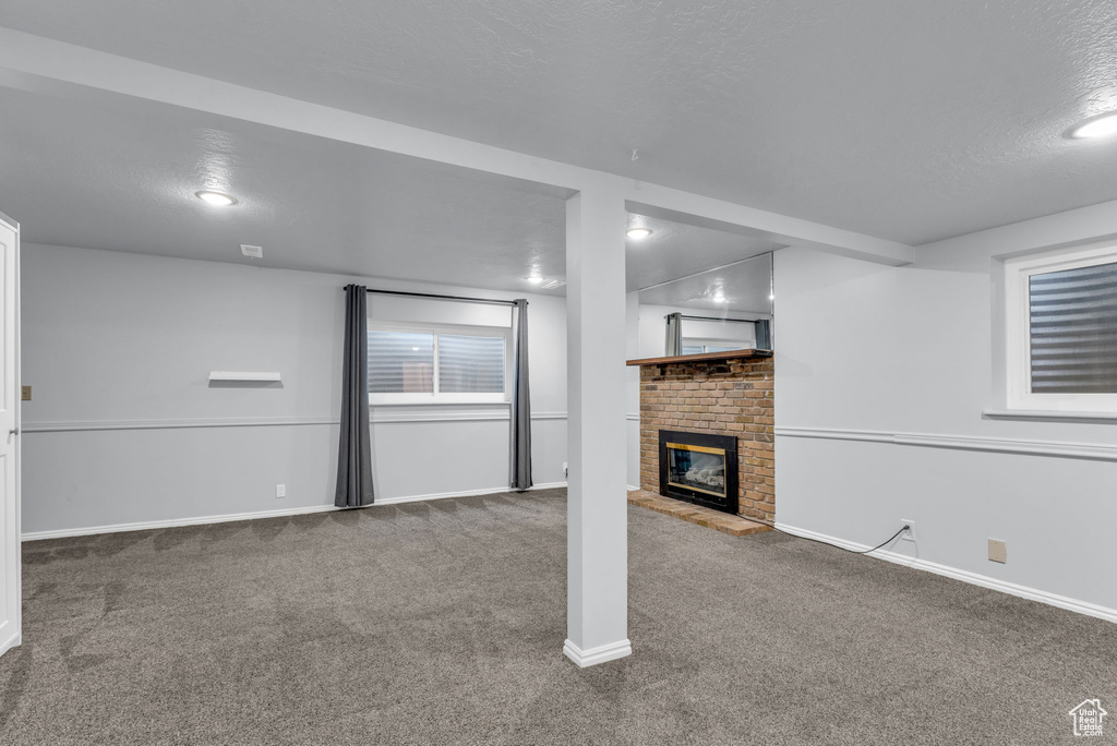 Below grade area featuring carpet, a brick fireplace, and baseboards