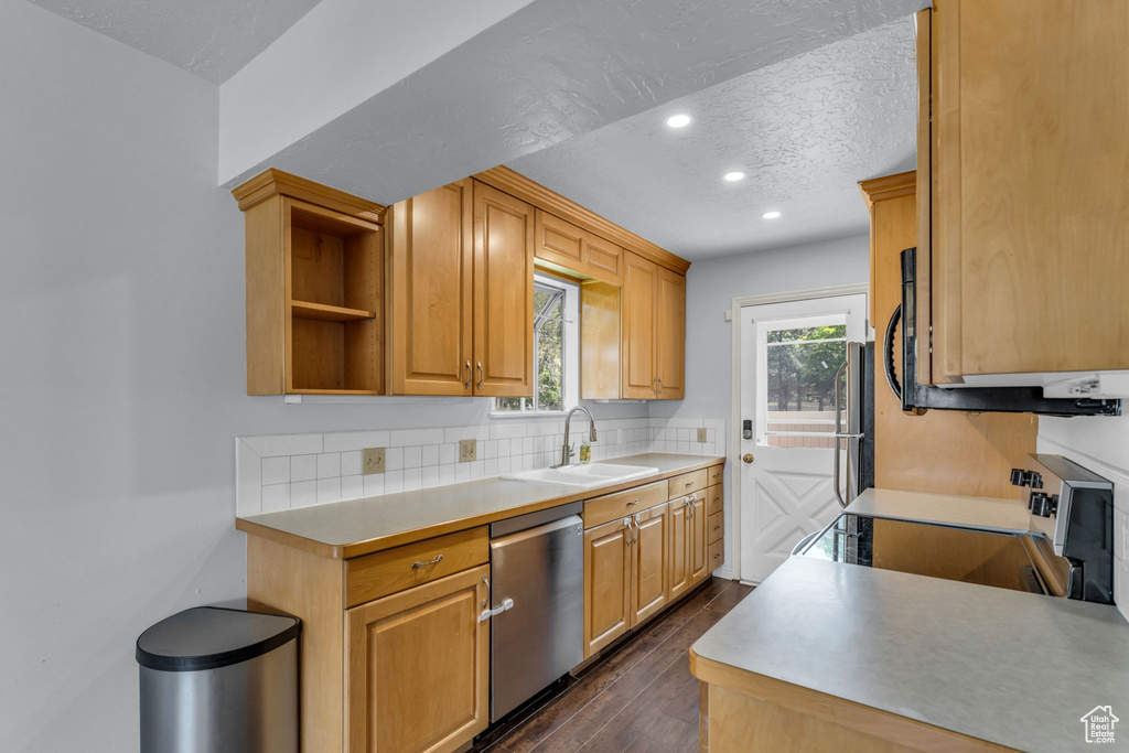 Kitchen featuring a sink, appliances with stainless steel finishes, recessed lighting, dark wood-style flooring, and decorative backsplash
