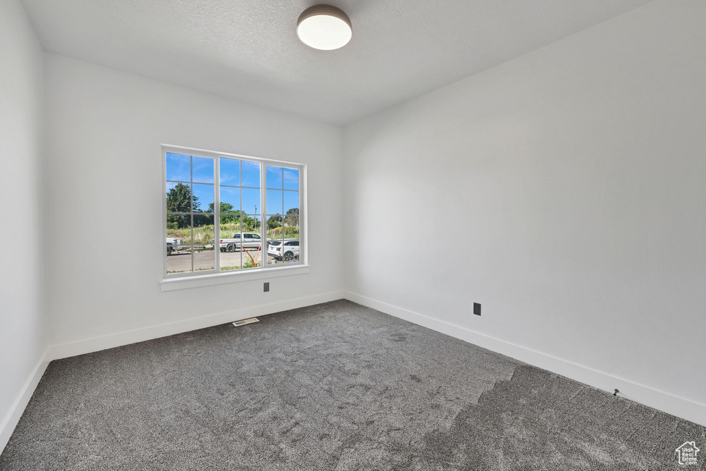 Empty room featuring dark carpet and baseboards